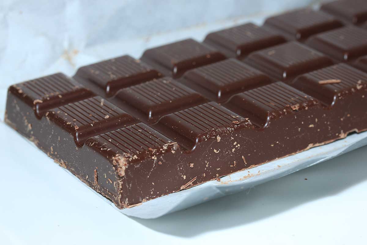Dark chocolate bar on white tabletop.